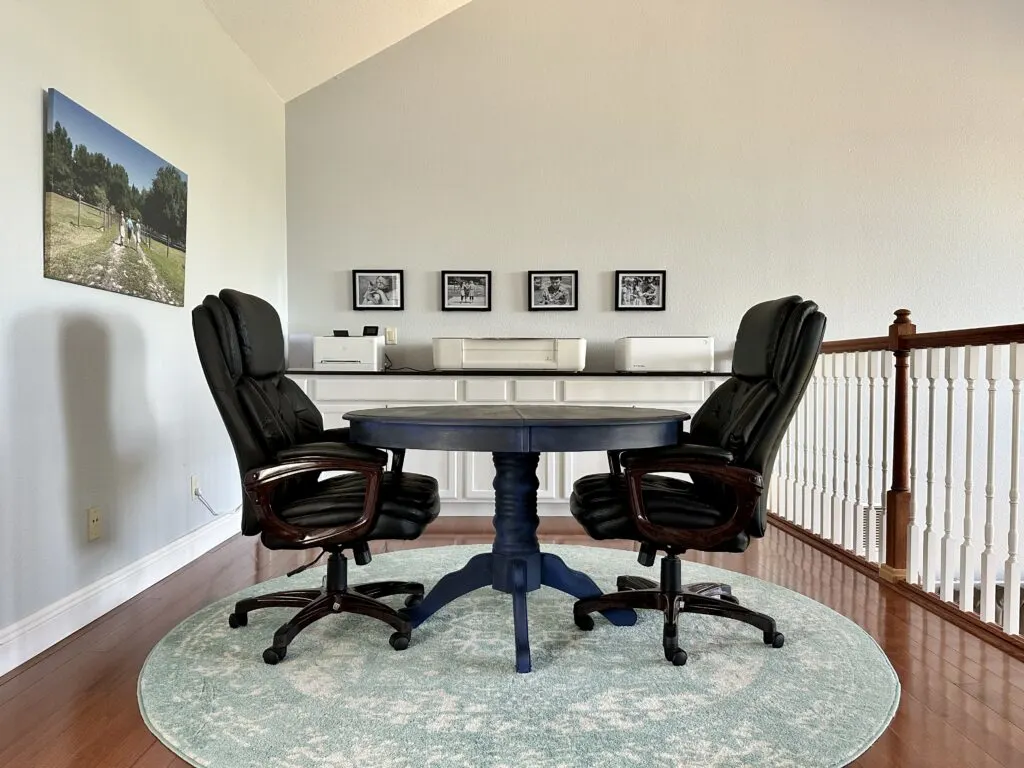 Blue table and two leather work chairs in a craft room and office space - cuttingforbusiness.com.